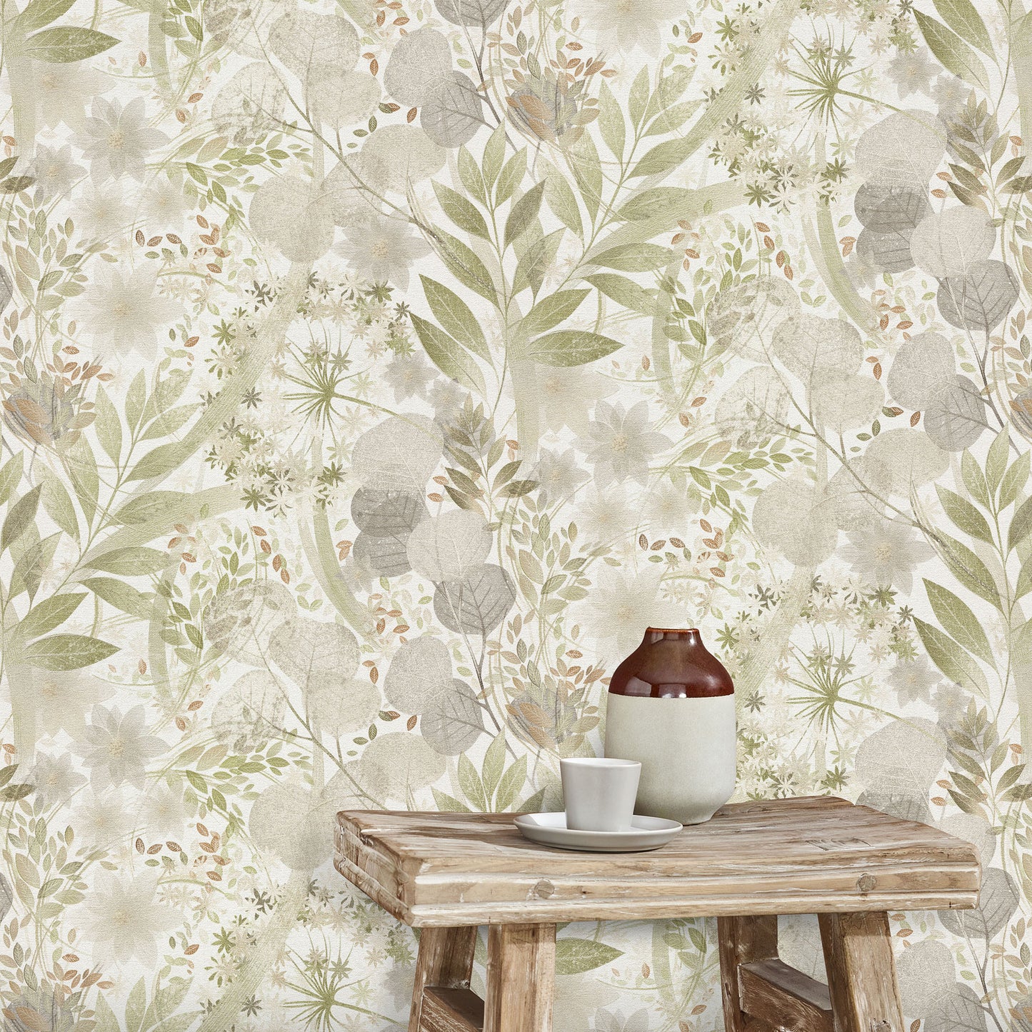 Botanical wallpaper in sage, beige and gray tones with leafy motifs; rustic wooden table holding a brown bottle and white cup.