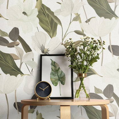 Wooden console with framed green leaf print, round black-gold clock, and glass vase with white flowers against leafy wallpaper.