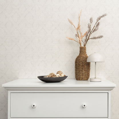 Gray wallpaper with a subtle pattern on the wall; foreground decor includes a white dresser, wicker vase with dried grasses, white dome lamp, and a black bowl with shells.