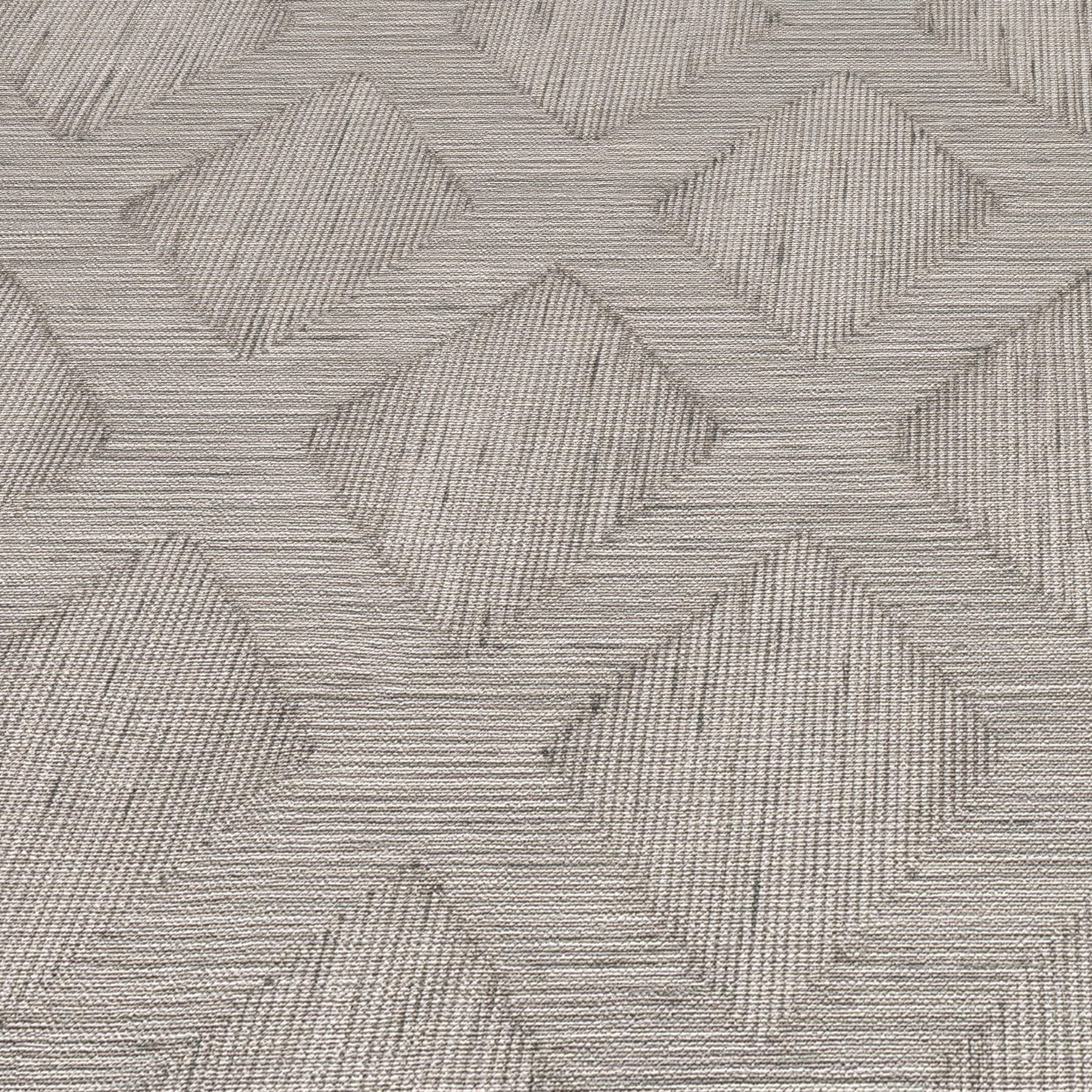 Grey woven rug with an interlocking diamond chevron pattern and subtle textured lines.
