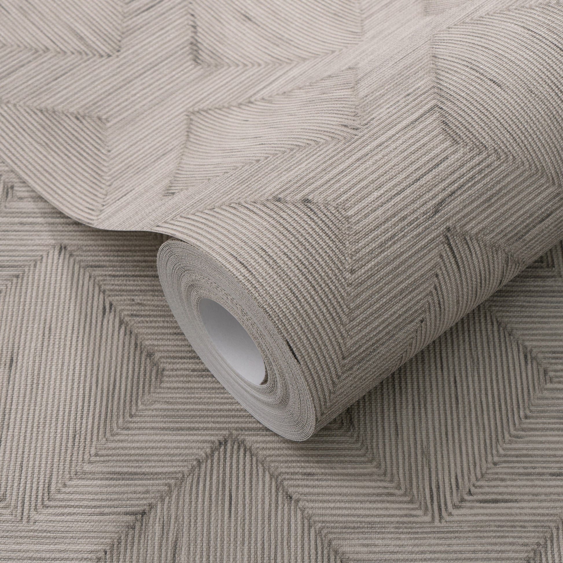 Beige-gray textured wallpaper roll with a subtle herringbone chevron pattern and fabric-like finish for walls.