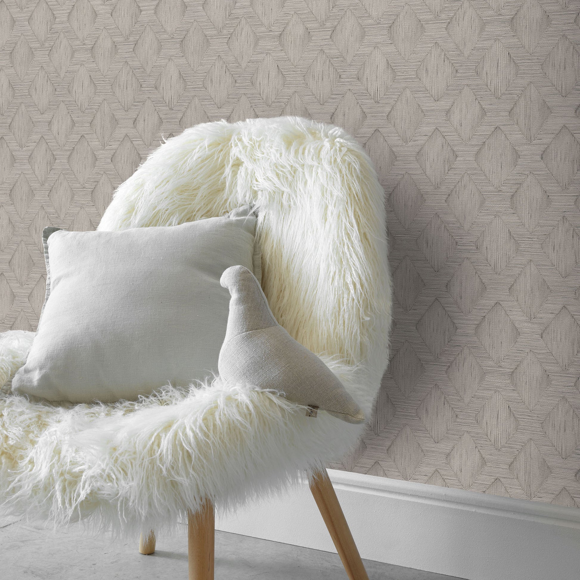 Cream shaggy faux fur chair with light gray cushion and curved plush pillow against geometric wallpaper.