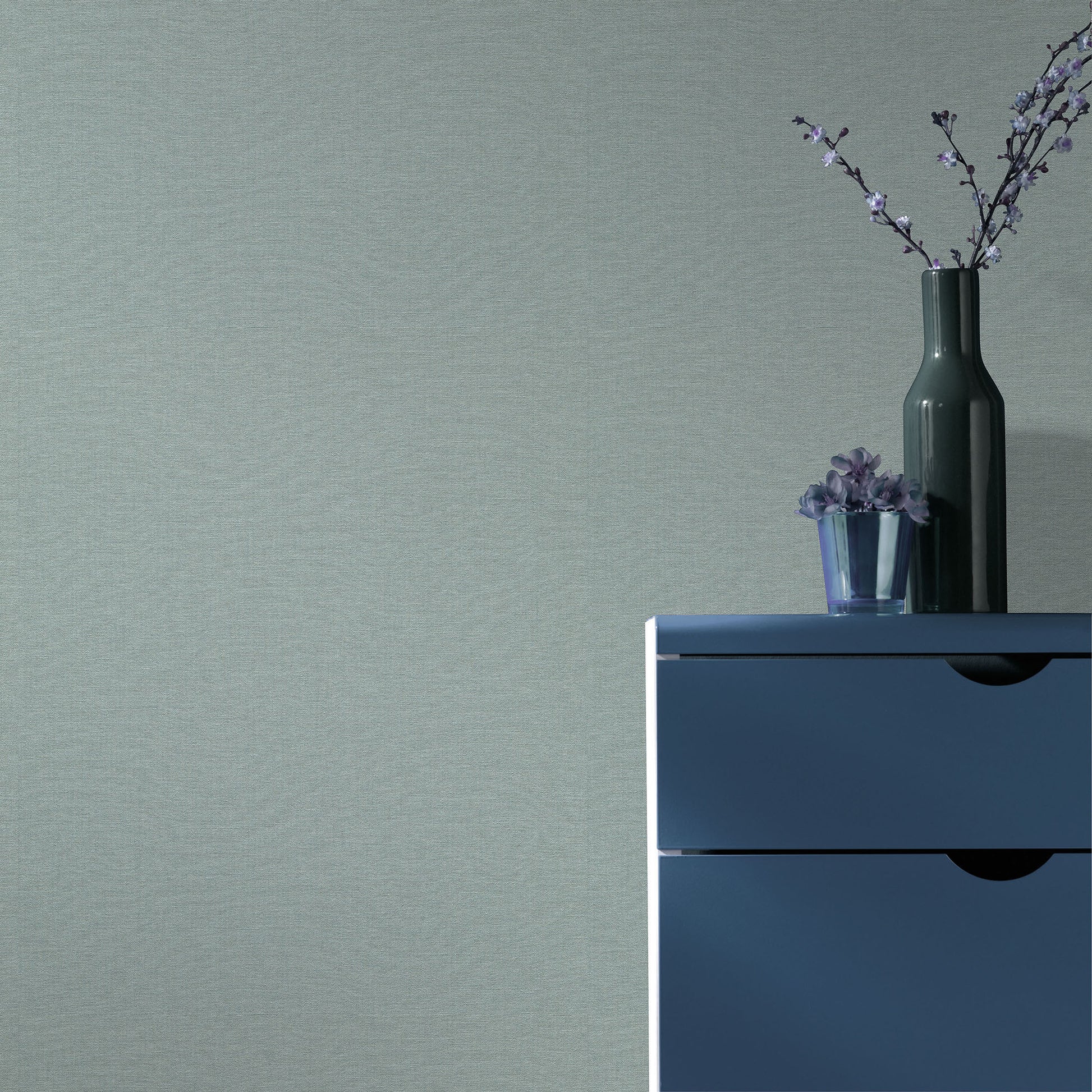 Teal wallpaper with a linen-like texture and a traditional pattern.