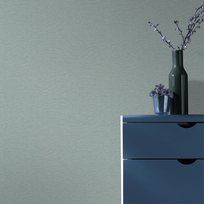 Teal wallpaper with a linen-like texture and a traditional pattern.