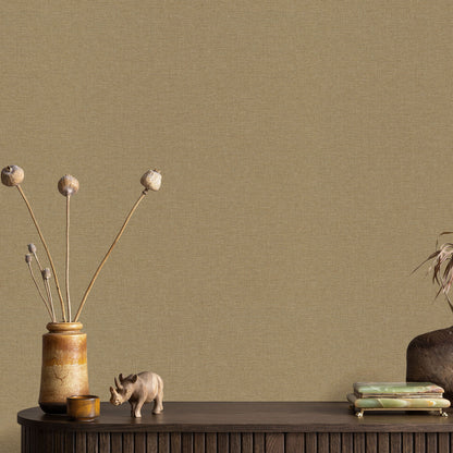 Linen Serenity Yellow wallpaper (traditional yellow pattern) on a beige wall behind a rustic decor scene: dark wooden table, tan ceramic vase with dried stems, a tiny pig figurine, and a stack of books.