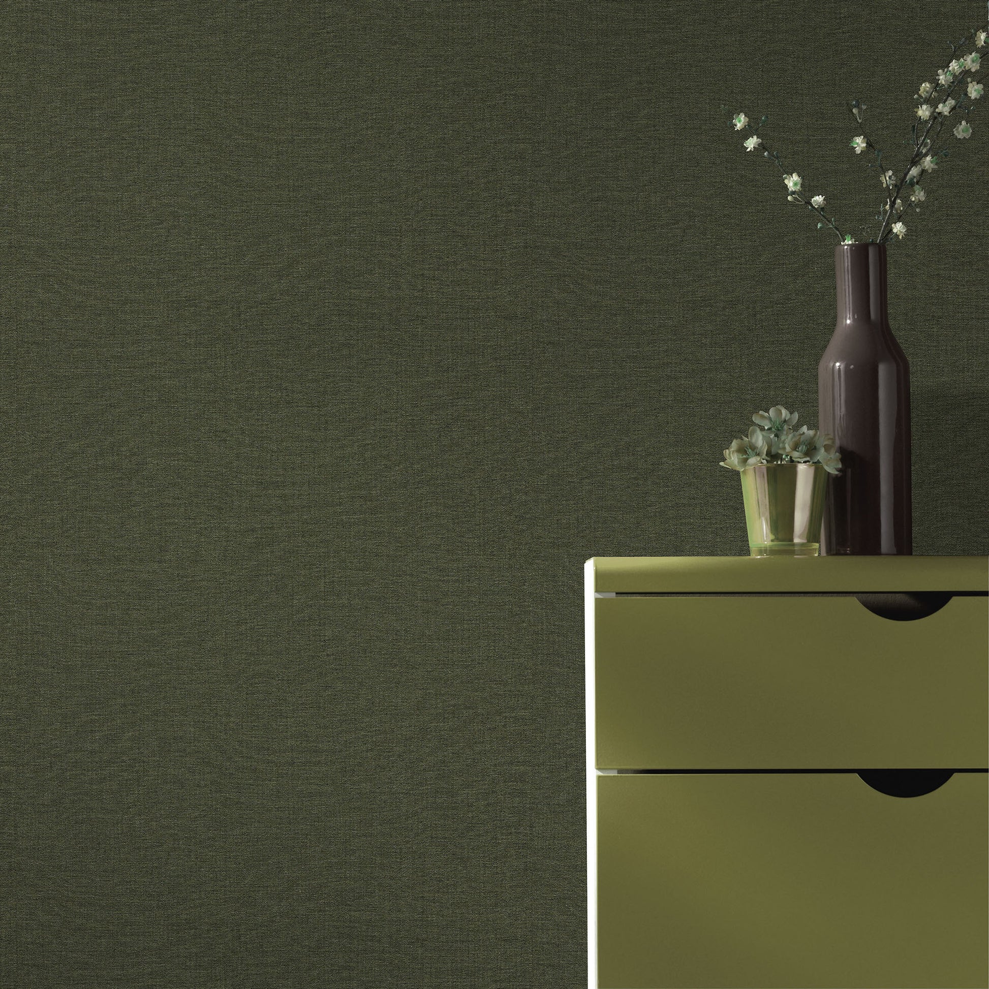 Olive-green wallpaper pattern on a wall, with a tall dark vase and a small succulent on a surface.