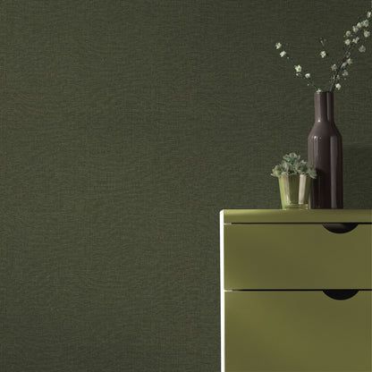 Olive-green wallpaper pattern on a wall, with a tall dark vase and a small succulent on a surface.