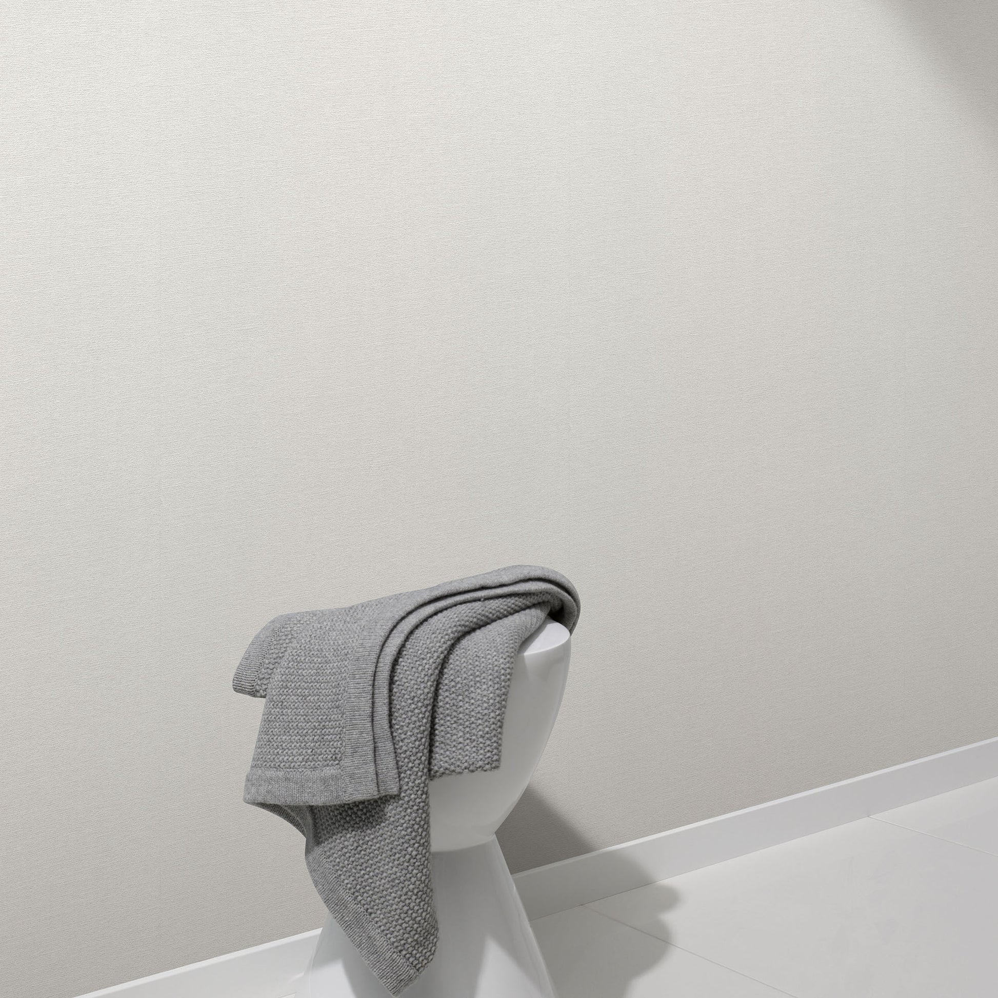 Light grey linen-textured wallpaper on a white wall in a minimal modern setting.
