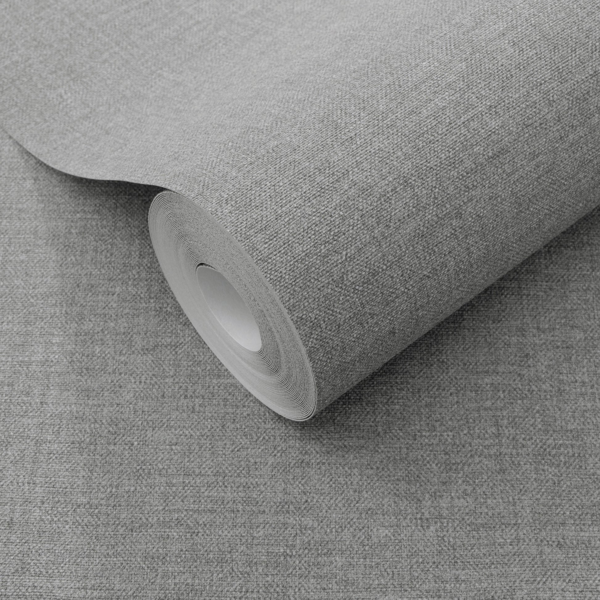Rolled gray wallpaper with a subtle linen-like texture on a matching gray surface.