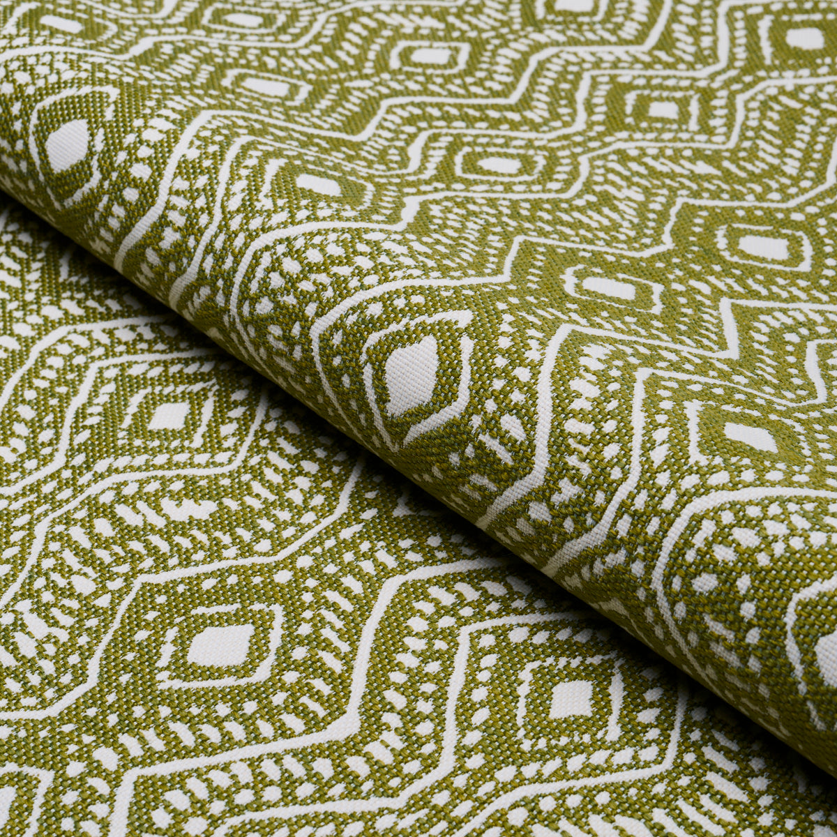 Rolled olive green and white geometric woven fabric with a diamond lattice pattern, ideal for upholstery or drapery.