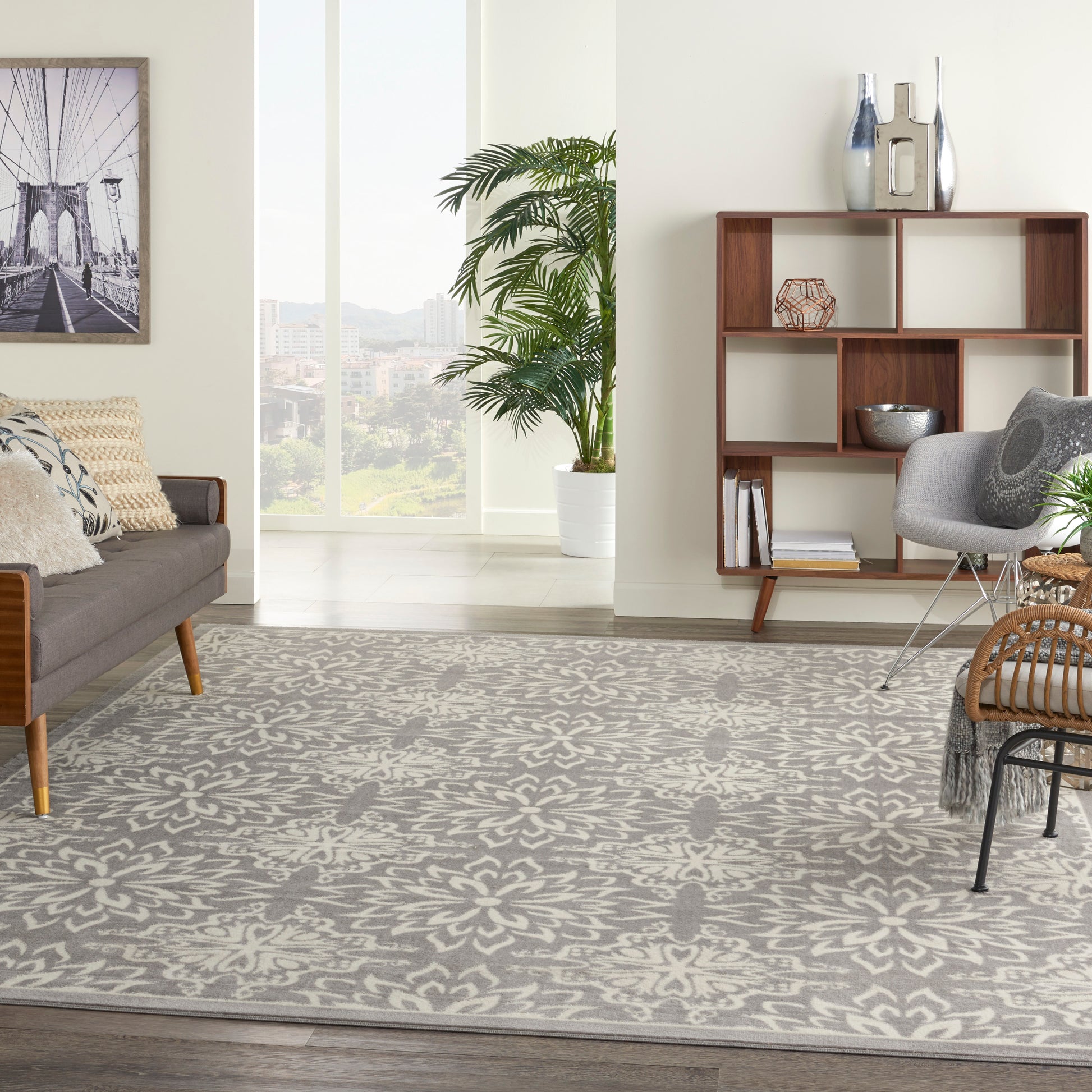 Modern living room with a gray floral-patterned rug, mid-century sofa, wooden shelves, and a potted palm.