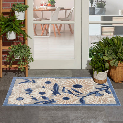 Rectangular woven doormat with cream daisies and blue centers on a blue border; outdoor entry rug.