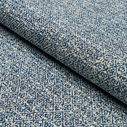 Rolled blue & white geometric patterned fabric with a diamond motif and woven texture, suitable for upholstery or drapery.