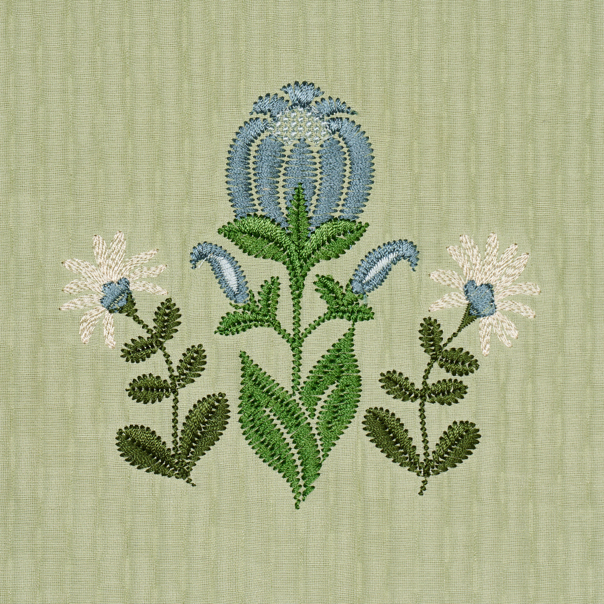Sage-green textured fabric with blue and green embroidery; central arching bloom with leafy stems.