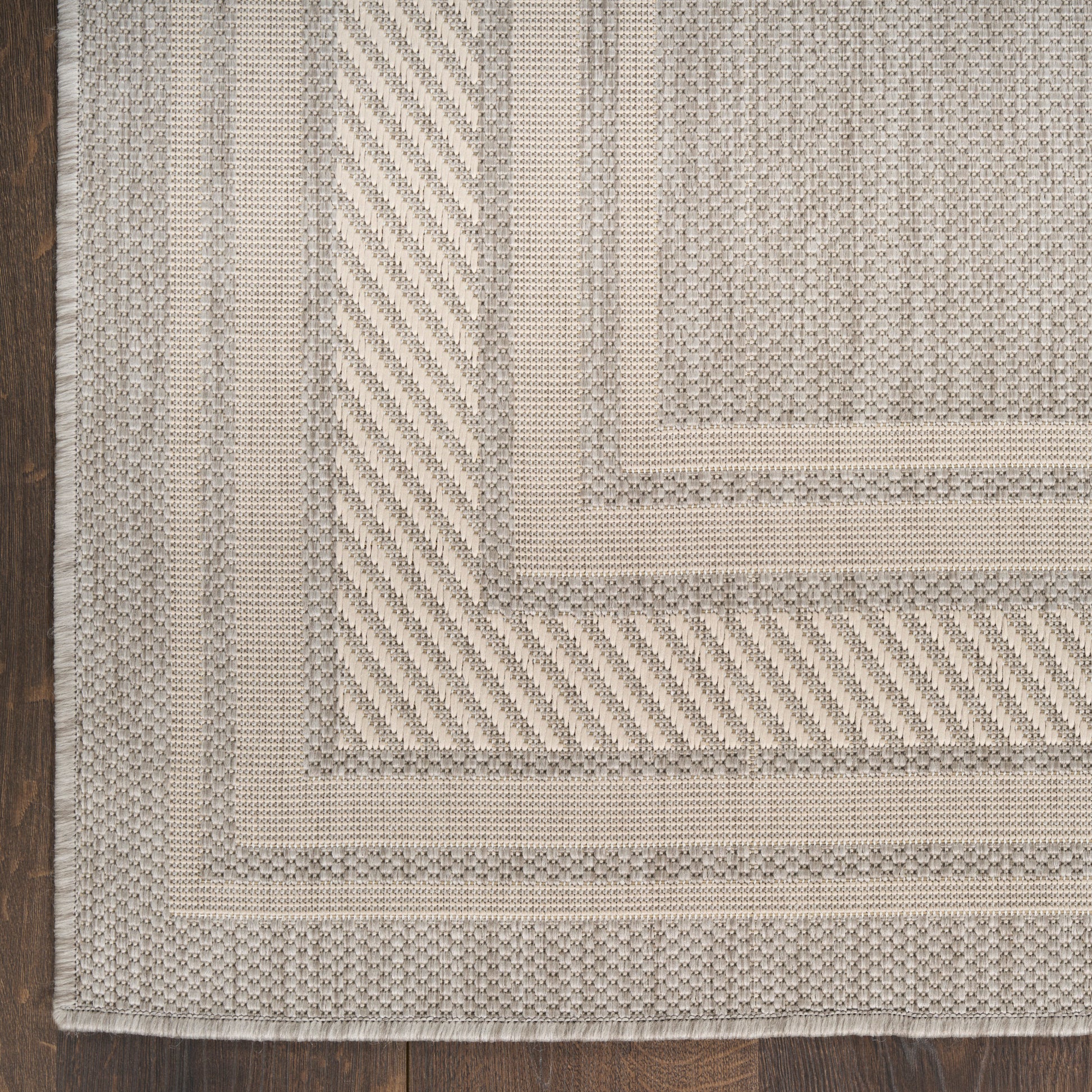 Beige and taupe woven rug with layered rectangular borders, textured surface and subtle edge fringe.