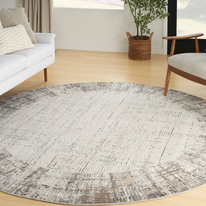 Circular rug with muted gray-beige pattern; modern living room with white sofa, wooden chair, and plant.