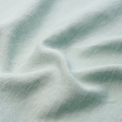 Mint green cotton-like fabric with subtle texture and soft drape in flowing folds.