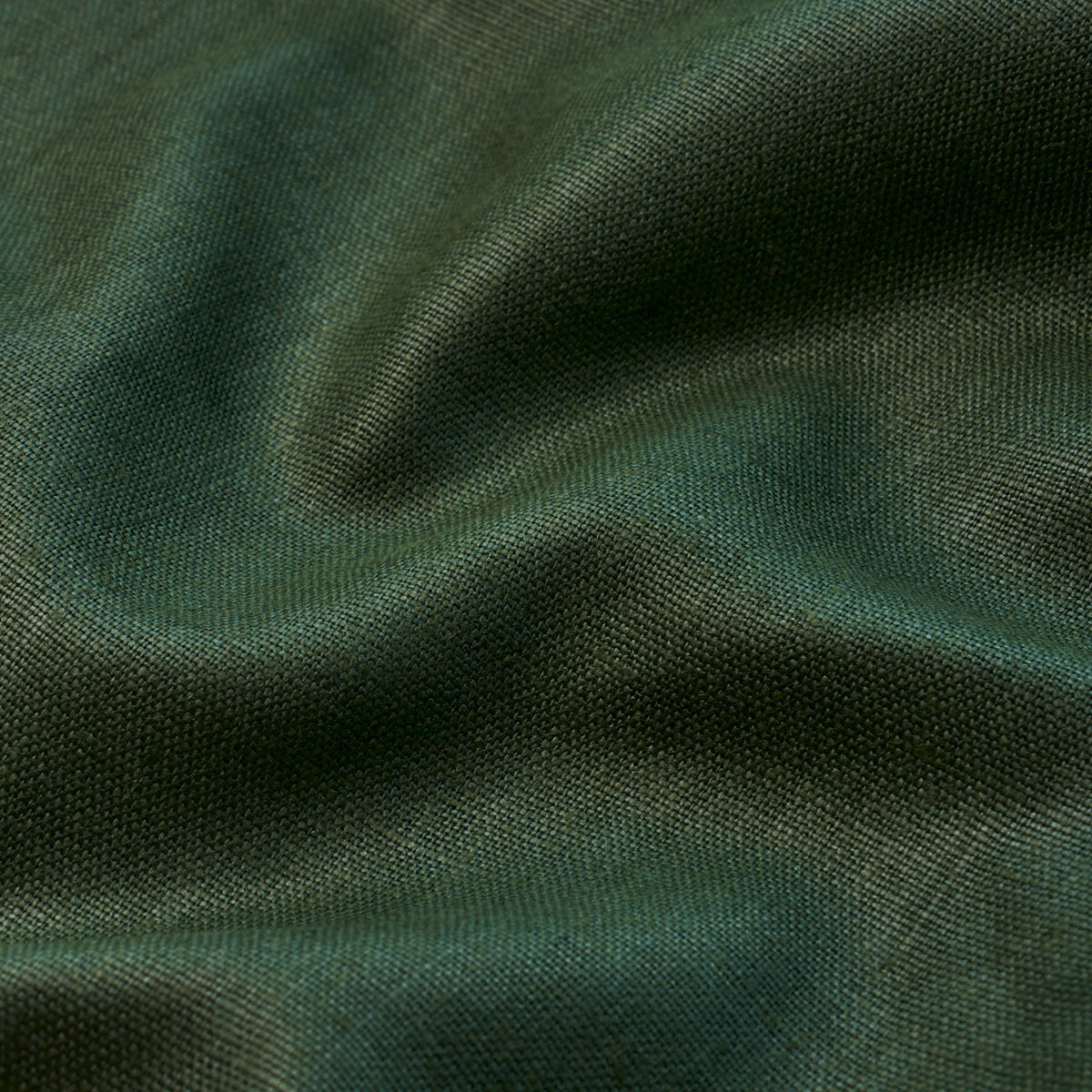 Dark green textured fabric close-up with soft folds and subtle sheen.