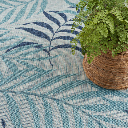 Woven turquoise rug with blue leaf patterns and textured natural fibers, paired with a potted plant in a wicker basket.