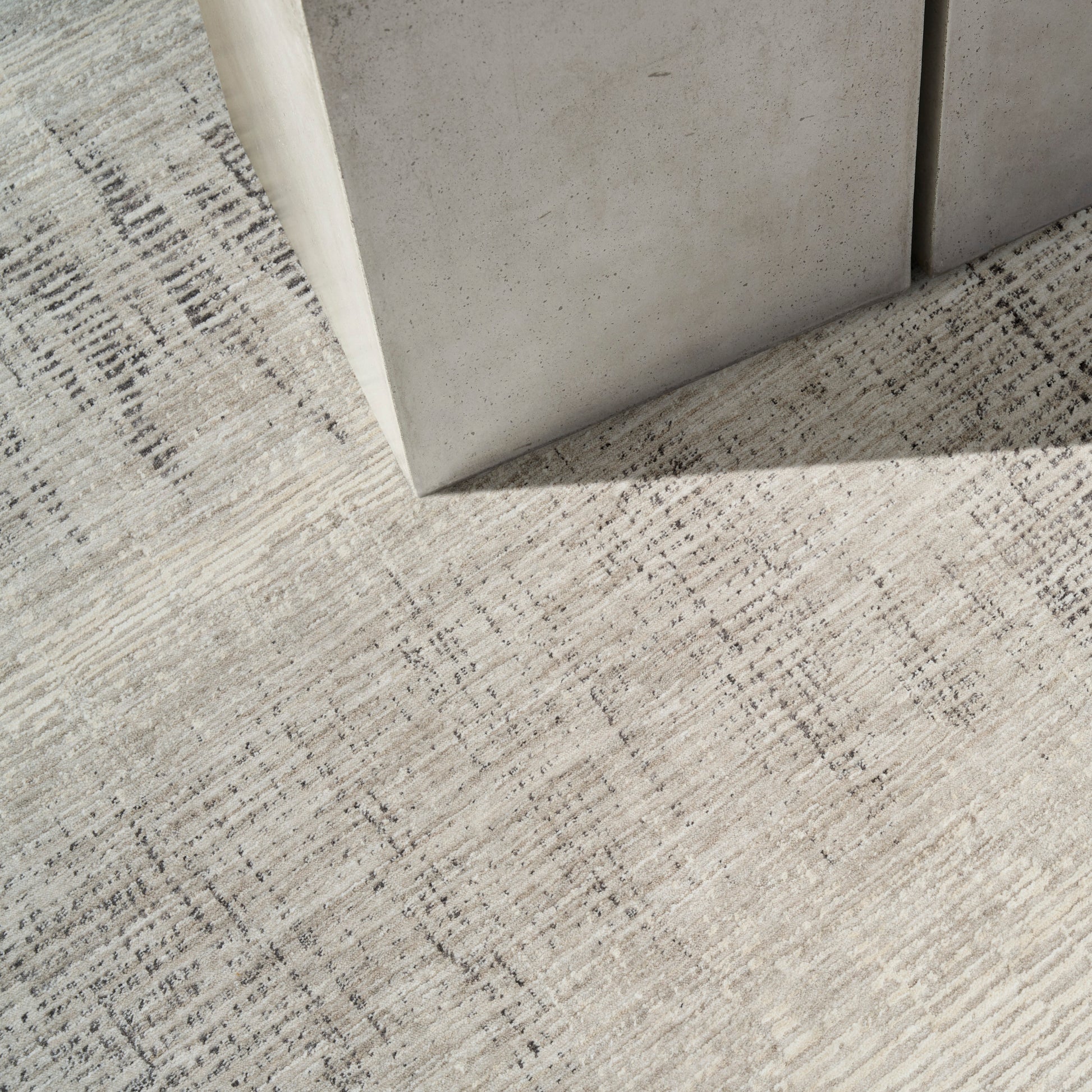 Concrete block pedestal on a beige patterned rug; industrial minimalist decor accent.