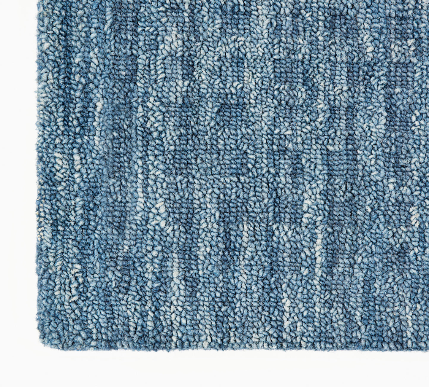 Blue textured shag rug with variegated light and dark blue fibers; soft loop-pile for indoor decor.