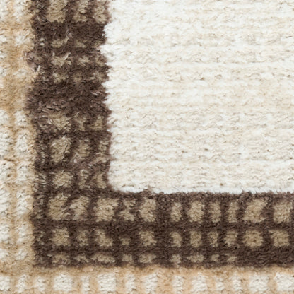Cream shag rug with dark brown border in square-pattern; plush, textured corner view.
