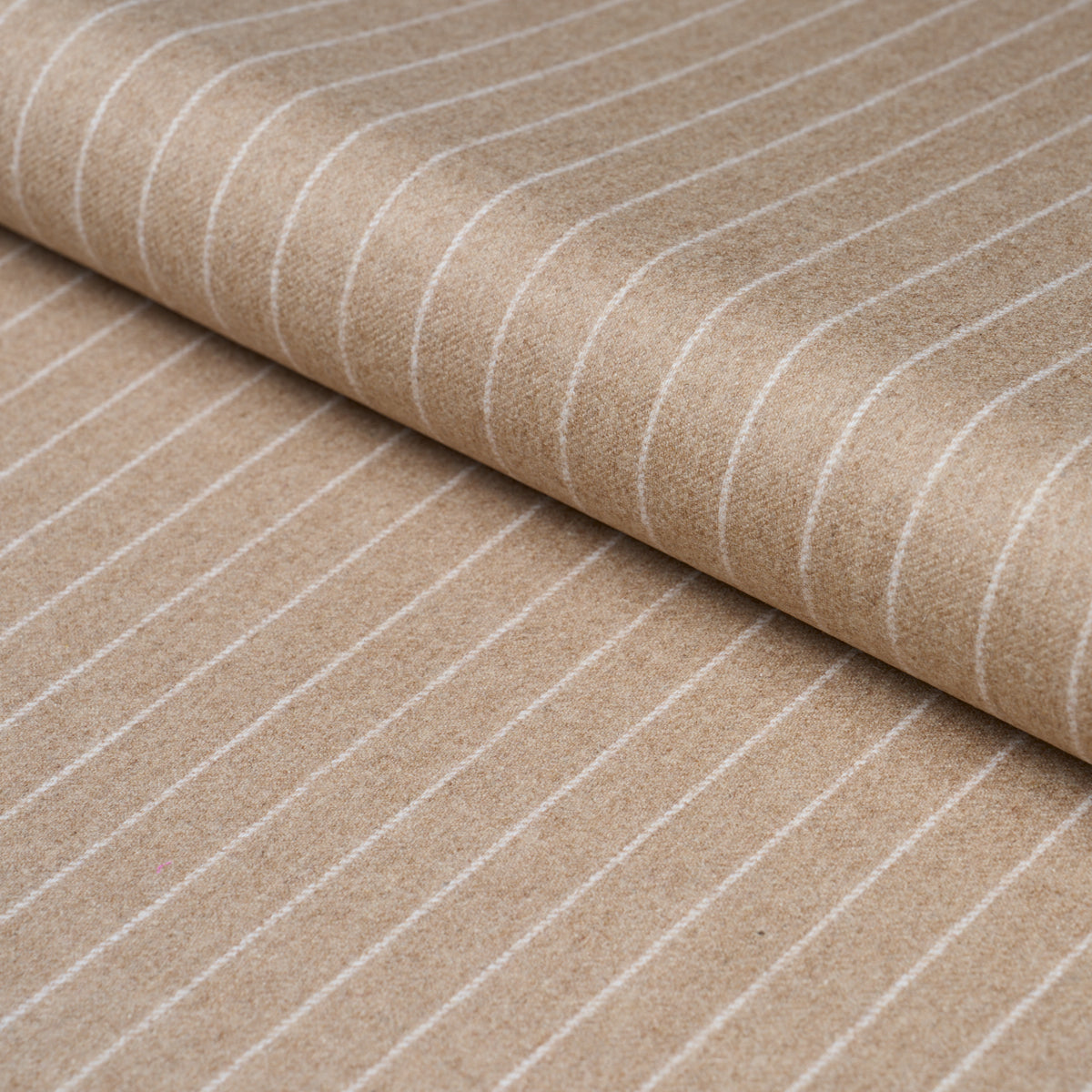 Beige fabric with thin white stripes, rolled textile; pinstripe suiting fabric suitable for apparel or upholstery.