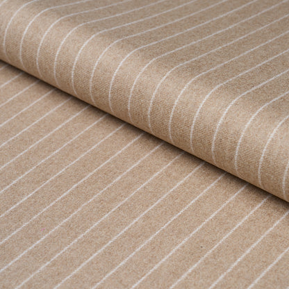 Beige fabric with thin white stripes, rolled textile; pinstripe suiting fabric suitable for apparel or upholstery.