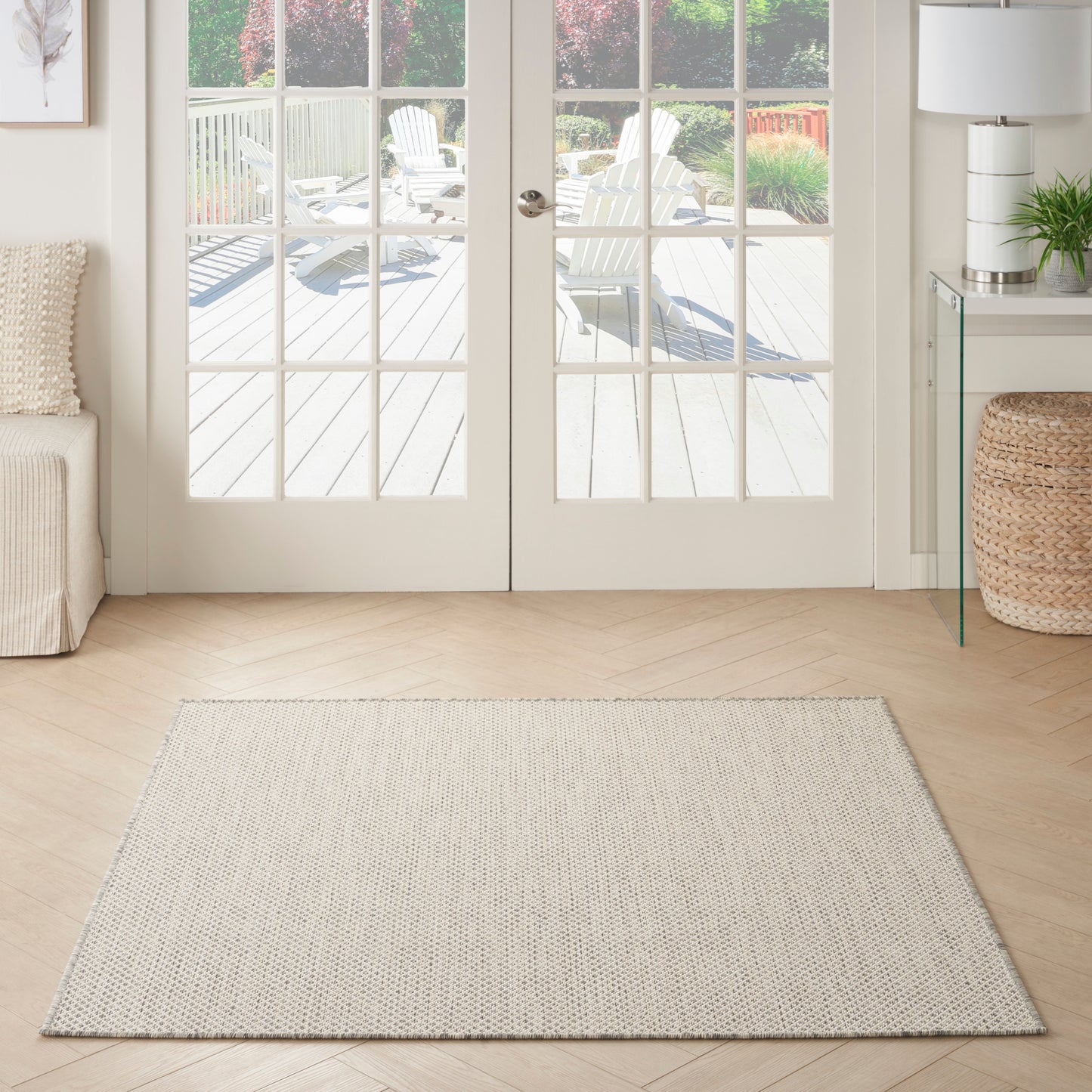 Rectangular textured beige rug on light wood floor in a bright living room with French doors and wicker basket.
