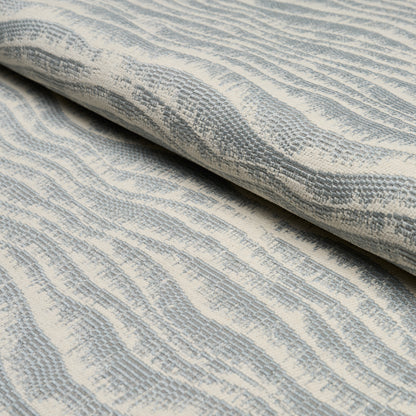Rolled light blue and ivory woven fabric with soft, wavy stripe texture, ideal for upholstery or drapery.