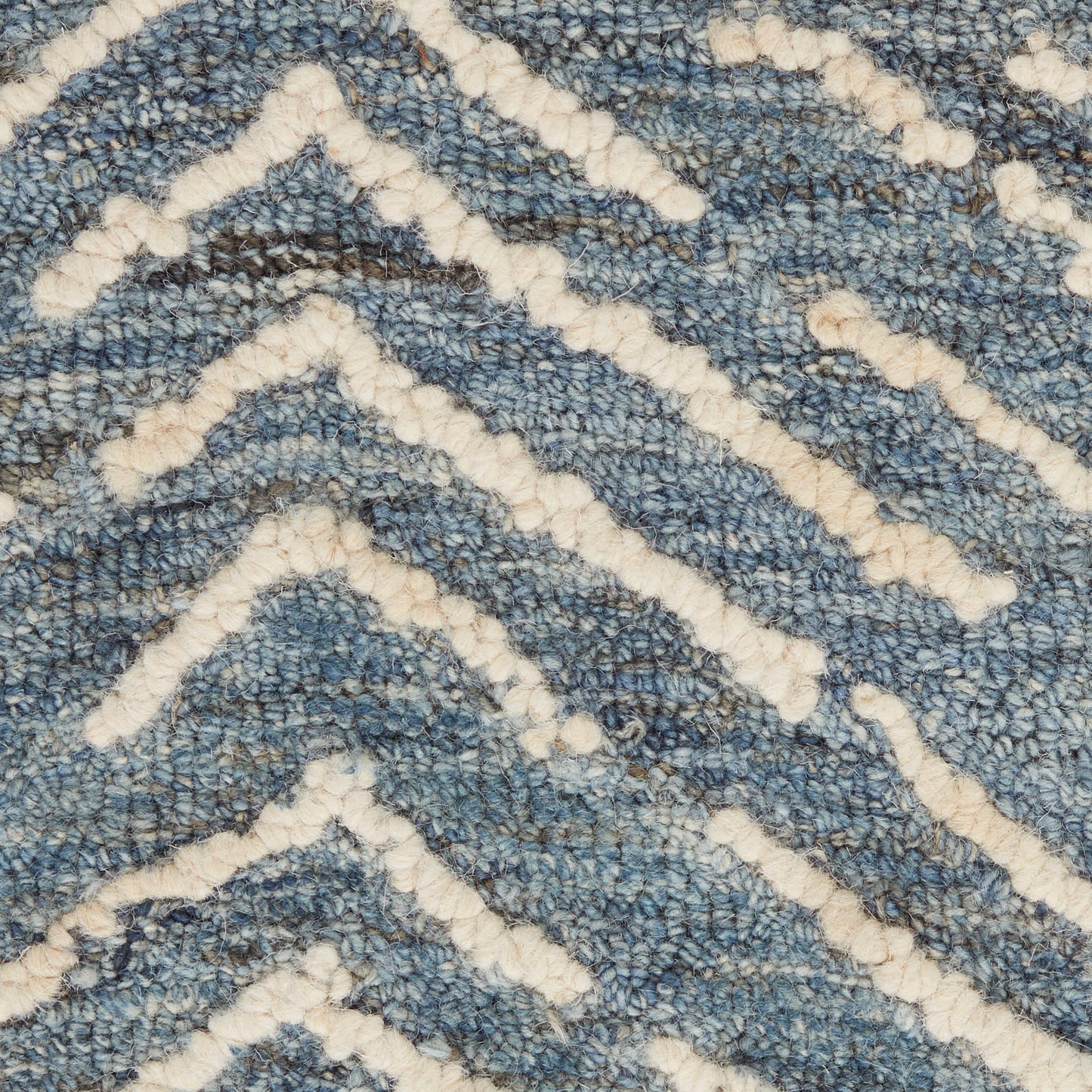 Blue textured rug with cream-white chevron zigzag pattern in plush loop pile.