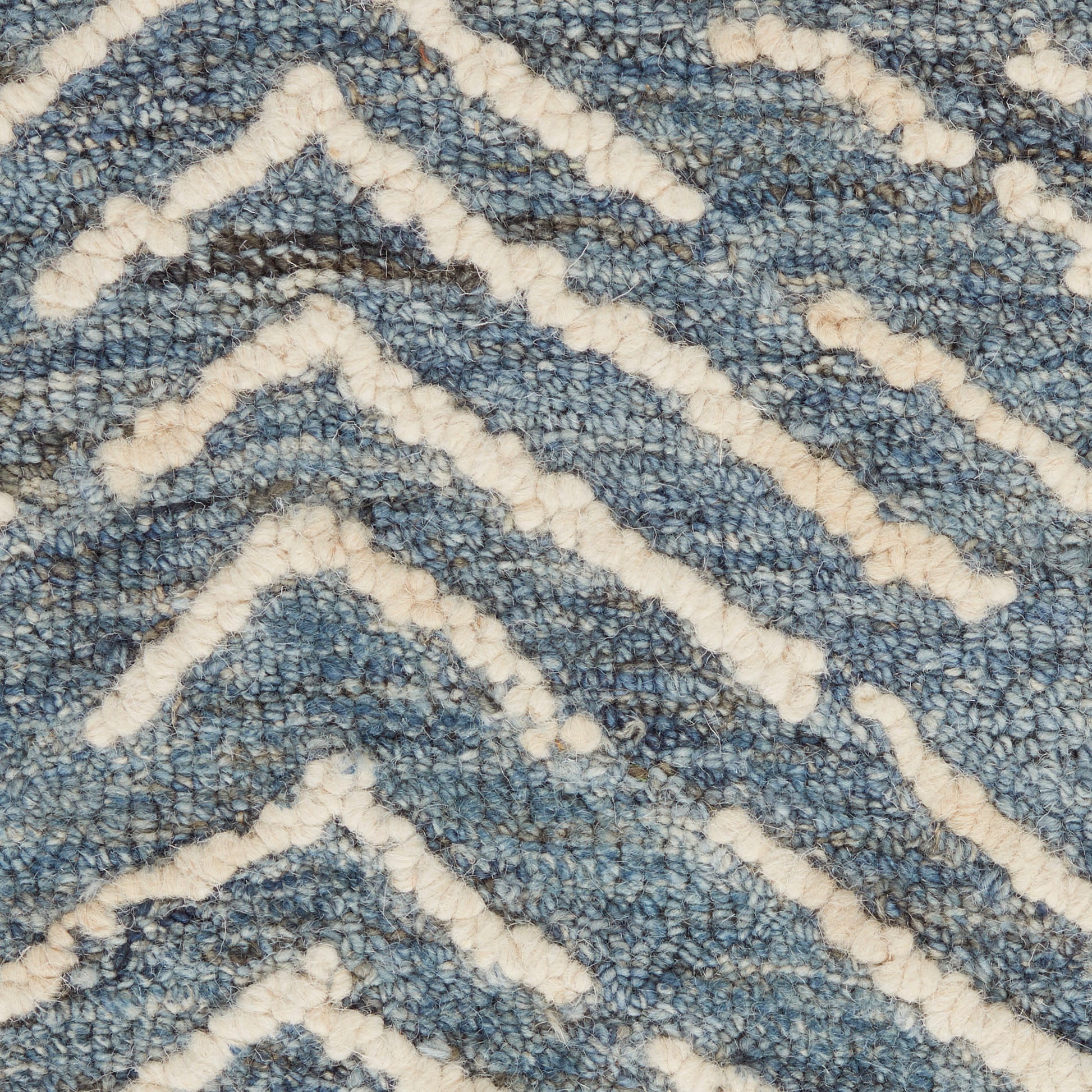 Blue textured rug with cream-white chevron zigzag pattern in plush loop pile.