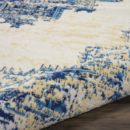 Blue and cream abstract patterned rug with plush pile and rolled edge on dark wood floor.
