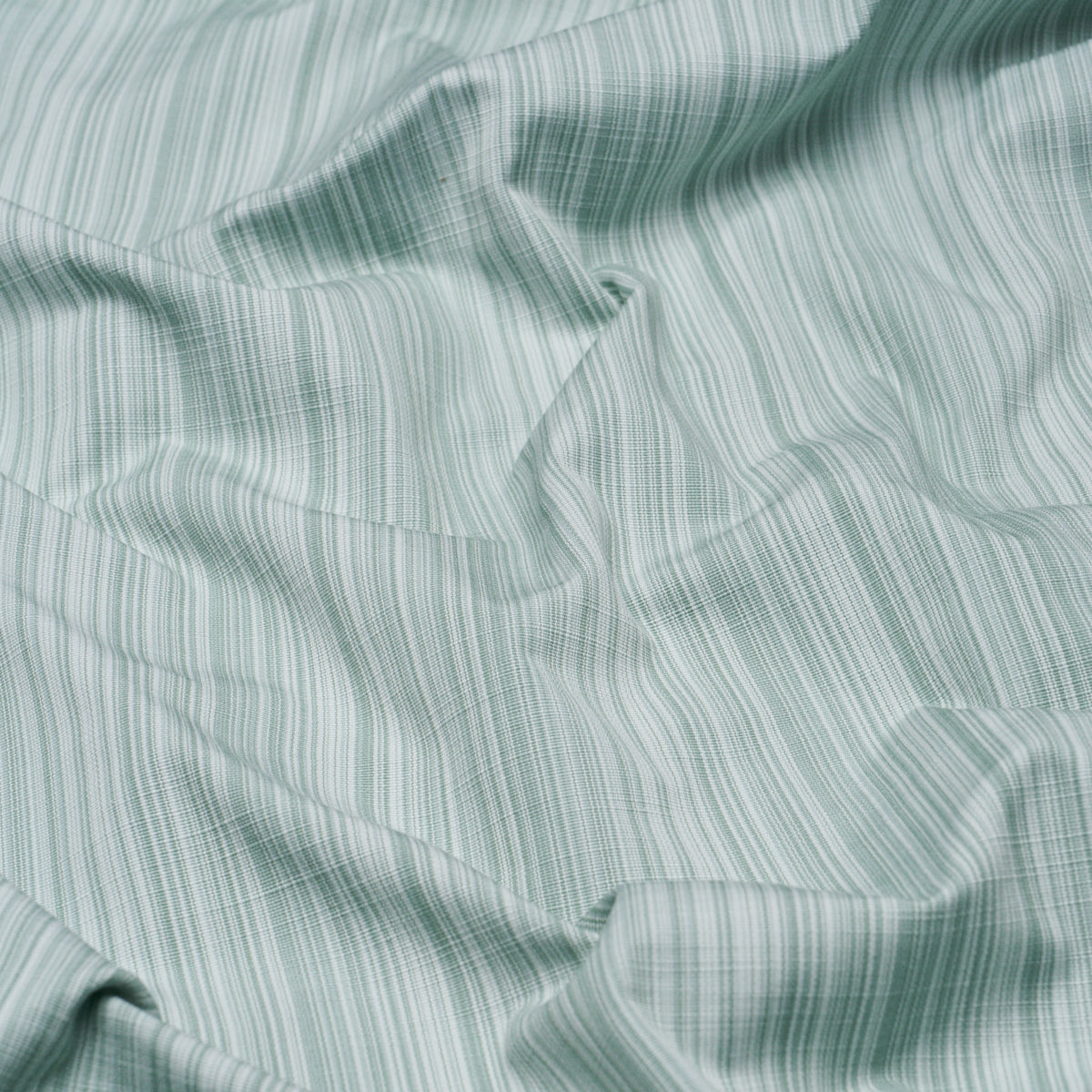 Mint green and white striped fabric with soft, wrinkled texture; lightweight woven material for shirts or bedding.