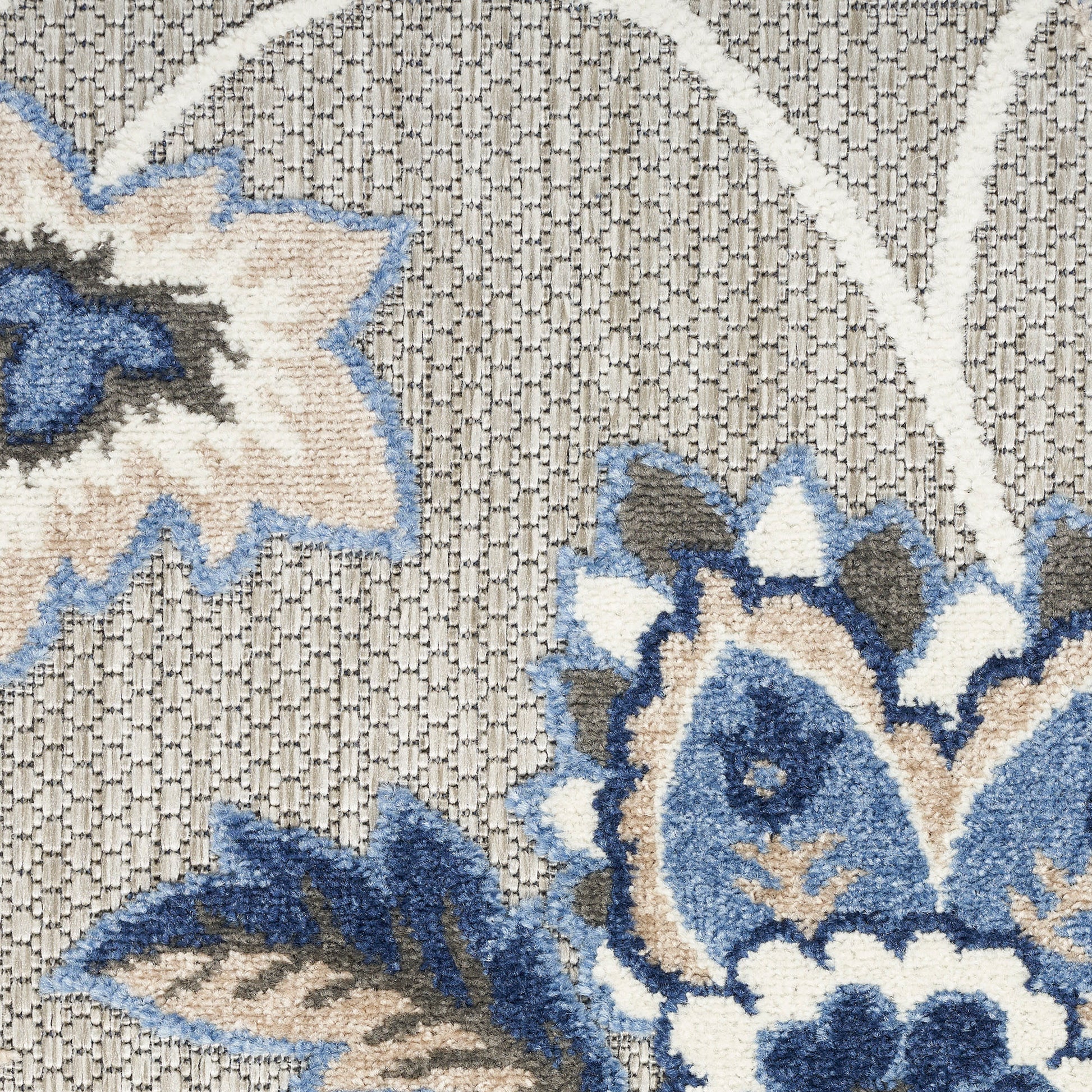 Textured woven rug with beige/cream base and cobalt blue floral motif.