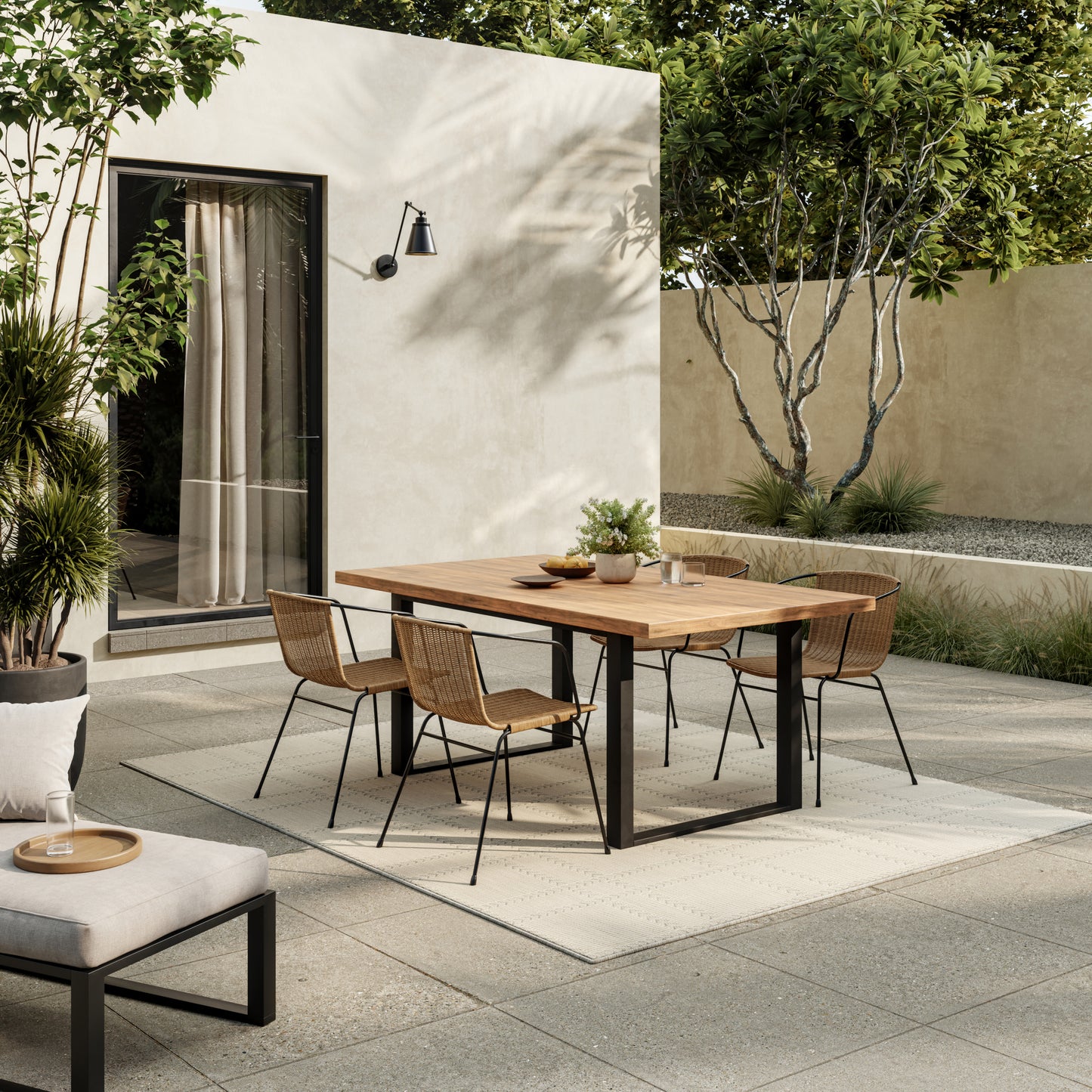 Modern outdoor dining set with wooden-top table, black metal frame, and six wicker chairs on a sunny patio.