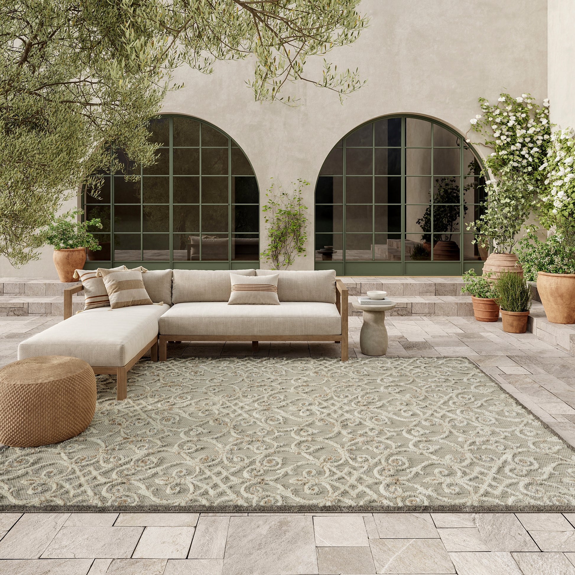 Beige rug 8' x 11' with a gray pattern in a sunlit courtyard featuring arched windows and potted plants.