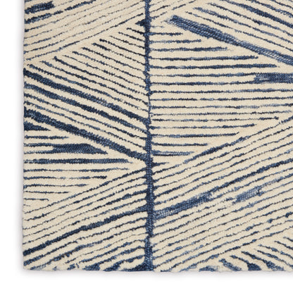 Beige tufted rug with navy blue linear geometric pattern; soft, modern decor accent.