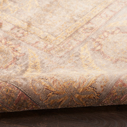 Persian-inspired area rug in muted gold, blush and taupe with an intricate floral border; plush texture, folded corner.