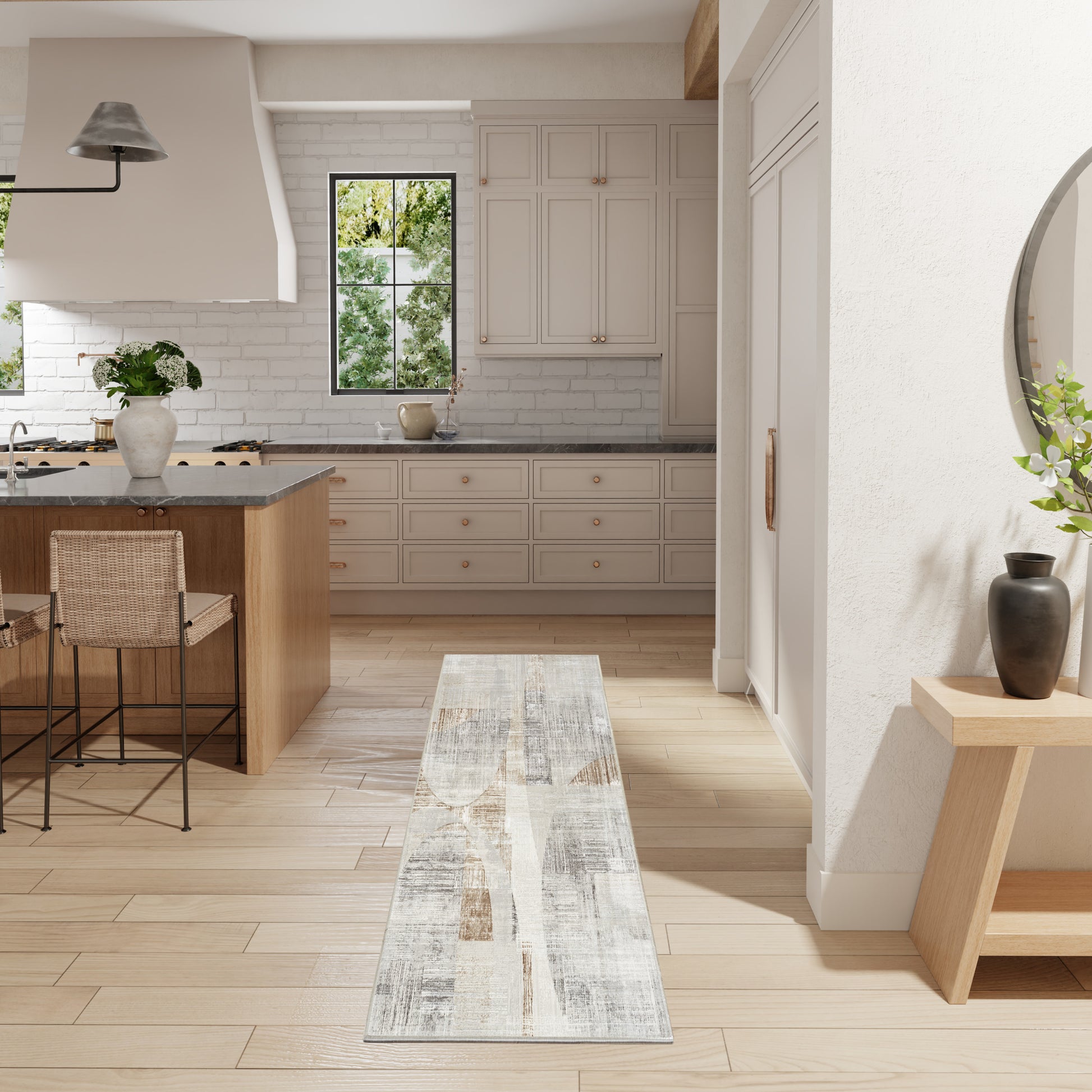 Bright modern kitchen with light wood floor, beige cabinets, gray countertops, island with wicker stools, narrow runner rug.