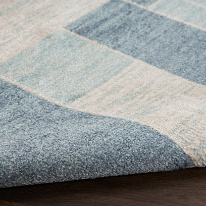 Blue patchwork rug with light and dark blue blocks; plush textured surface, ideal for living room decor.