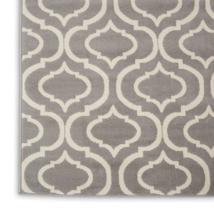 Gray rug with white geometric quatrefoil trellis pattern, woven textile, edge visible.