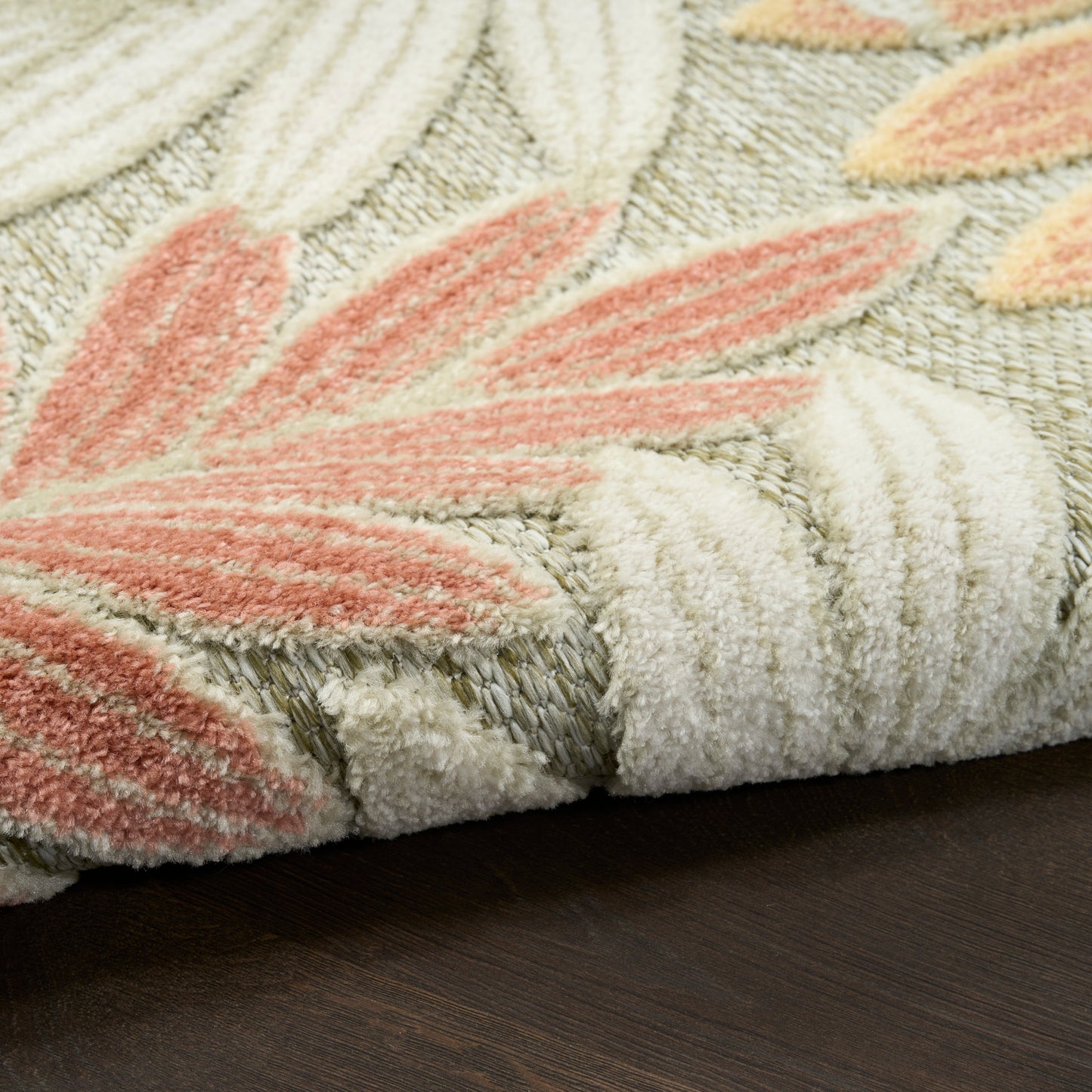 Soft tufted modern area rug with cream, peach and pink leaf pattern, plush pile, rolled edge, on dark wood floor
