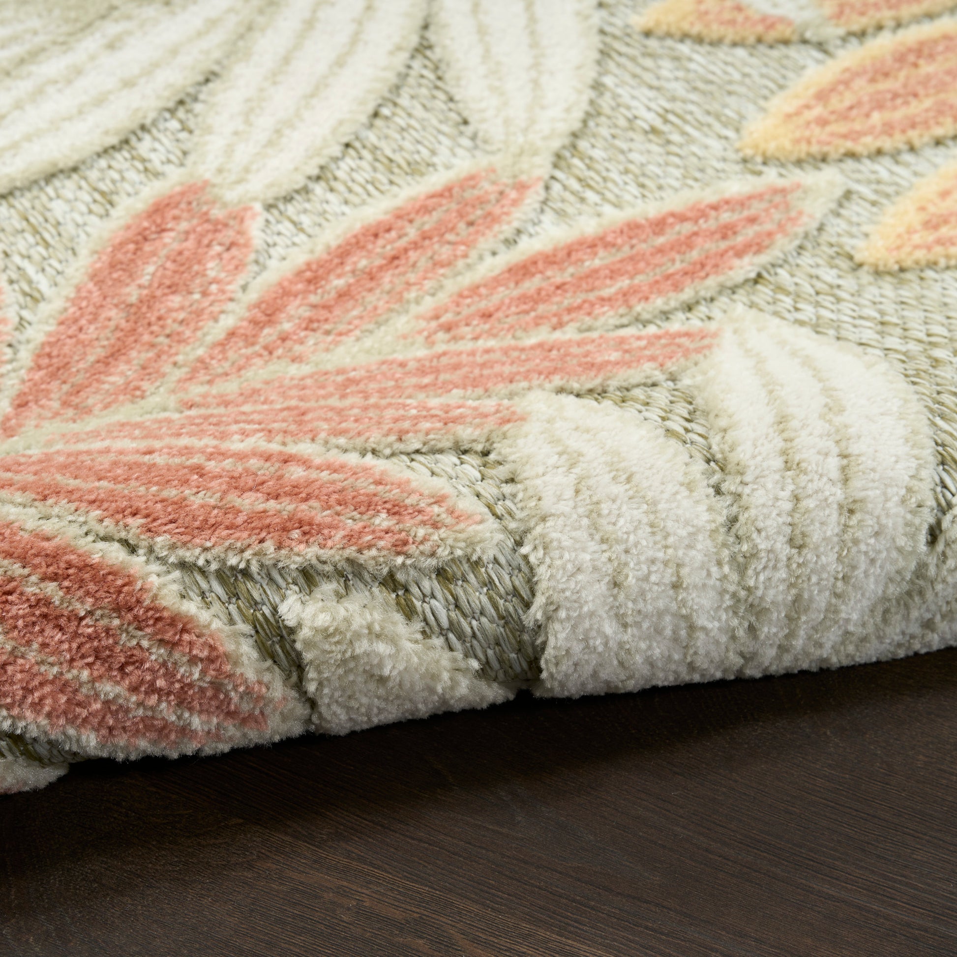 Soft tufted modern area rug with cream, peach and pink leaf pattern, plush pile, rolled edge, on dark wood floor