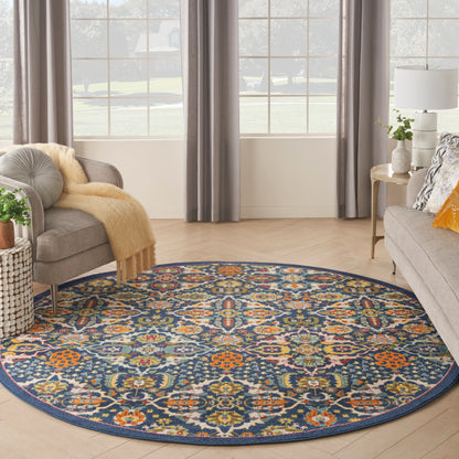 Round navy rug with vivid multicolor floral medallion pattern in a living room with gray sofa, curtains, and wooden floor.
