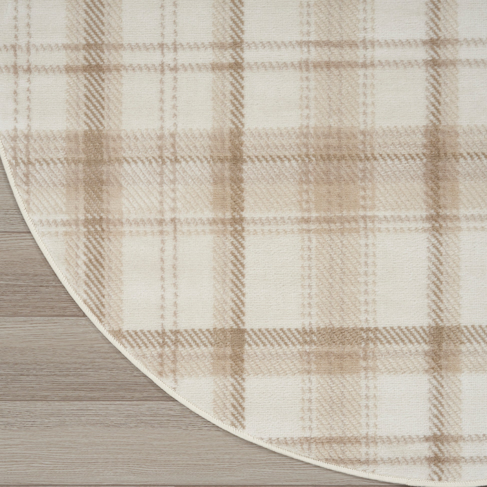 Beige plaid rug with cream & tan checks, curved edge, placed on light wooden floor.