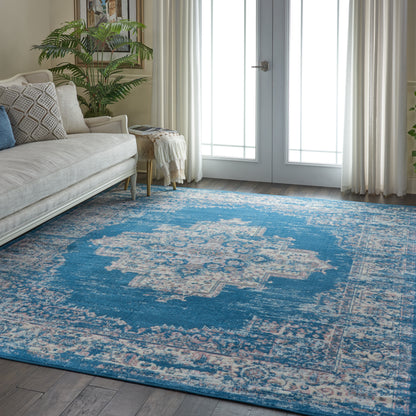 Blue oriental rug on wood floor in a living room with beige sofa, throw pillows, potted plant, and French doors.
