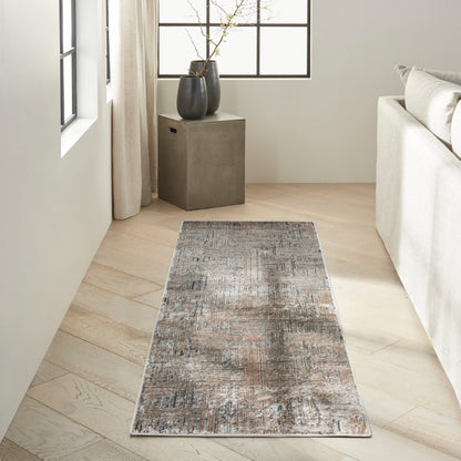 Rectangular distressed gray-blue rug on light wood floor beside a cream sofa and dark cube side table with vases.