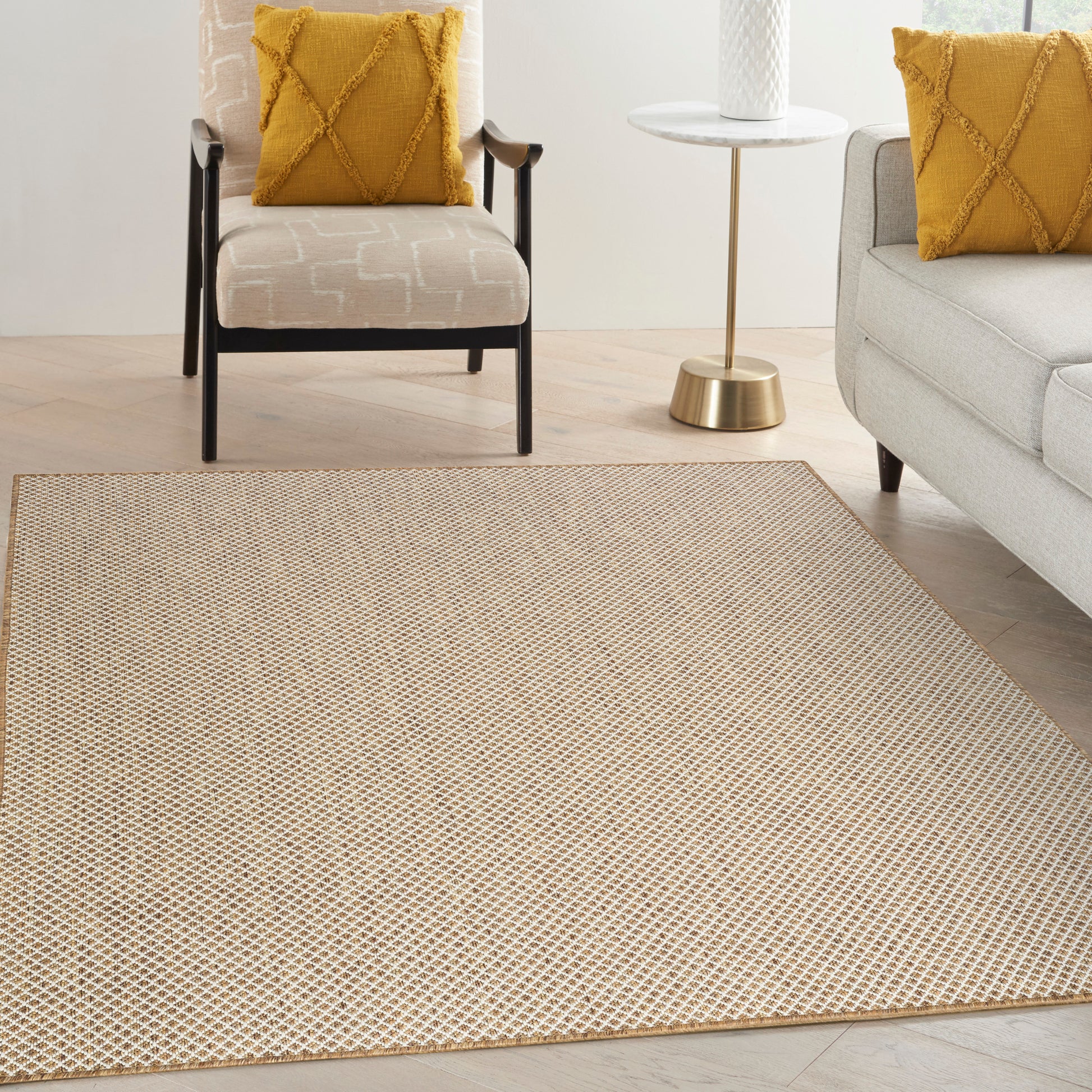 Beige woven area rug with tiny geometric pattern in a modern living room with mustard cushions and light furniture.
