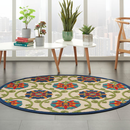 Round woven rug with blue border and vibrant red, blue, green floral motifs on beige field in a modern living room.